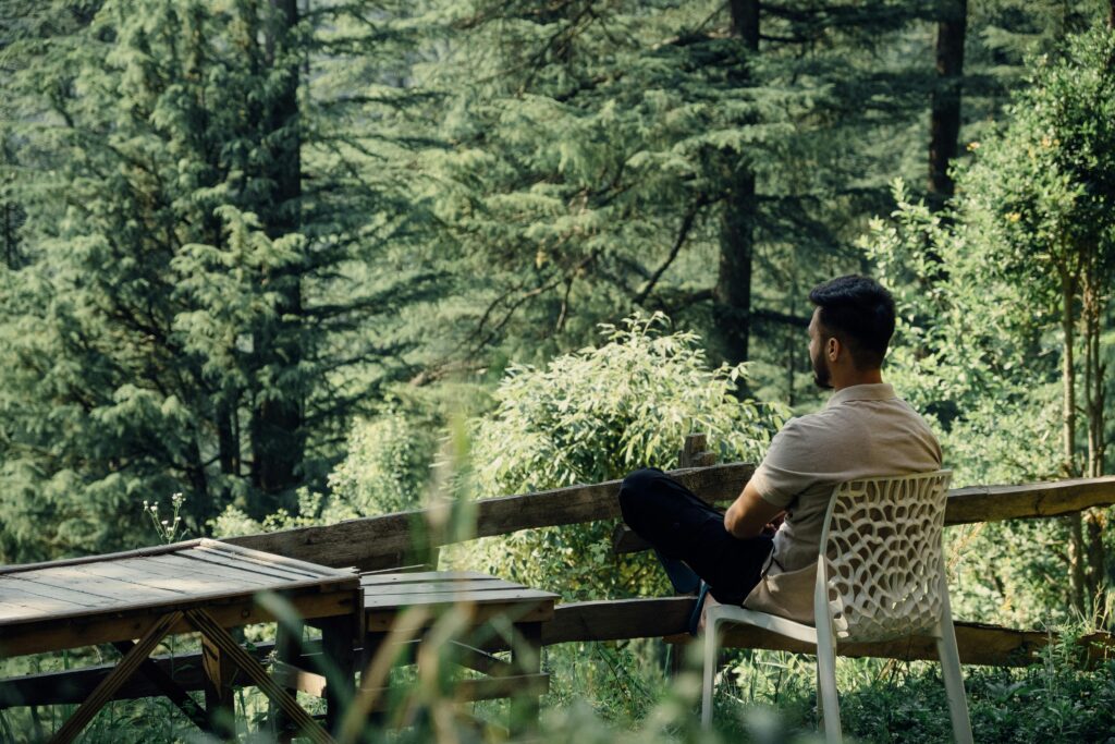 pexels-photo-27875431-27875431 A man relaxes in a forest setting in Jibhi, HP, India, enjoying nature's tranquility.
