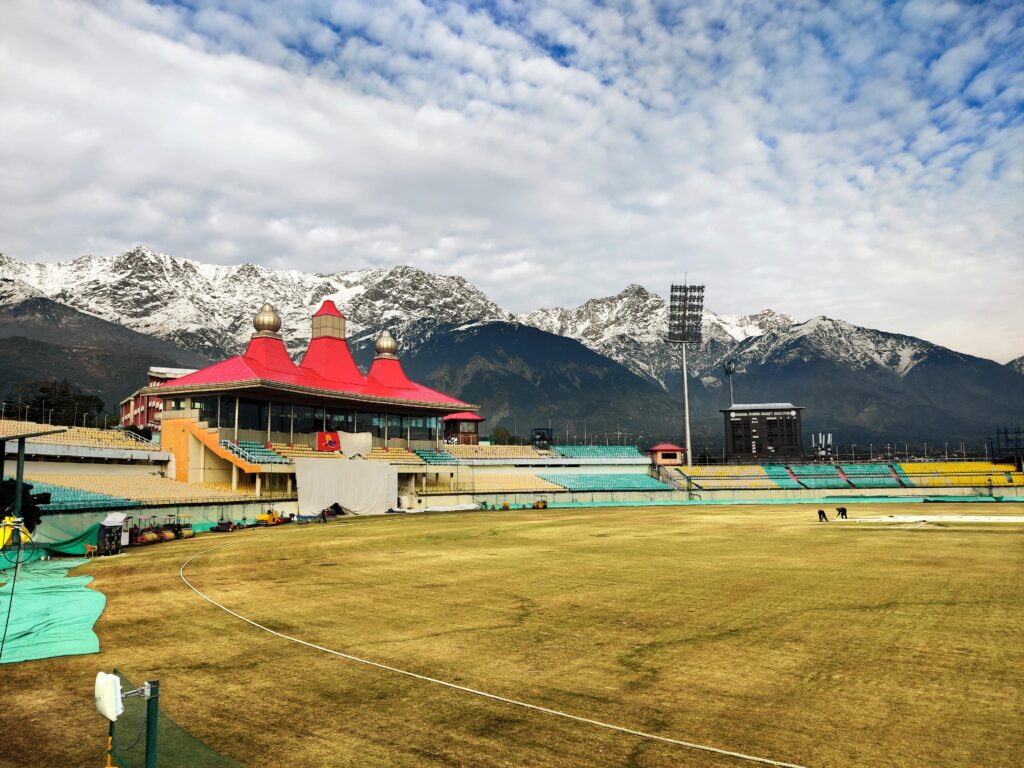 pexels-photo-5555967-5555967 Scenic view of Dharamshala Cricket Stadium against stunning snow-capped mountains in Himachal Pradesh, India.