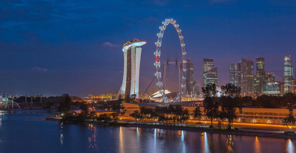 pexels-photo-711193-711193 Stunning night view of Singapore with Marina Bay Sands and Ferris Wheel, reflecting city lights on water.